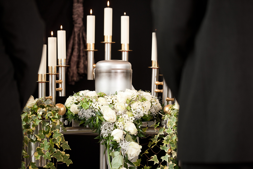 Urnenschmuck mit weißen Rosen und Blumen bei einer würdevollen Trauerfeier